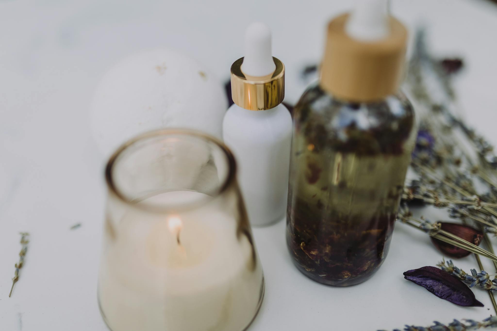 A calming spa setup featuring an aromatherapy candle, essential oils, and dried lavender for relaxation.