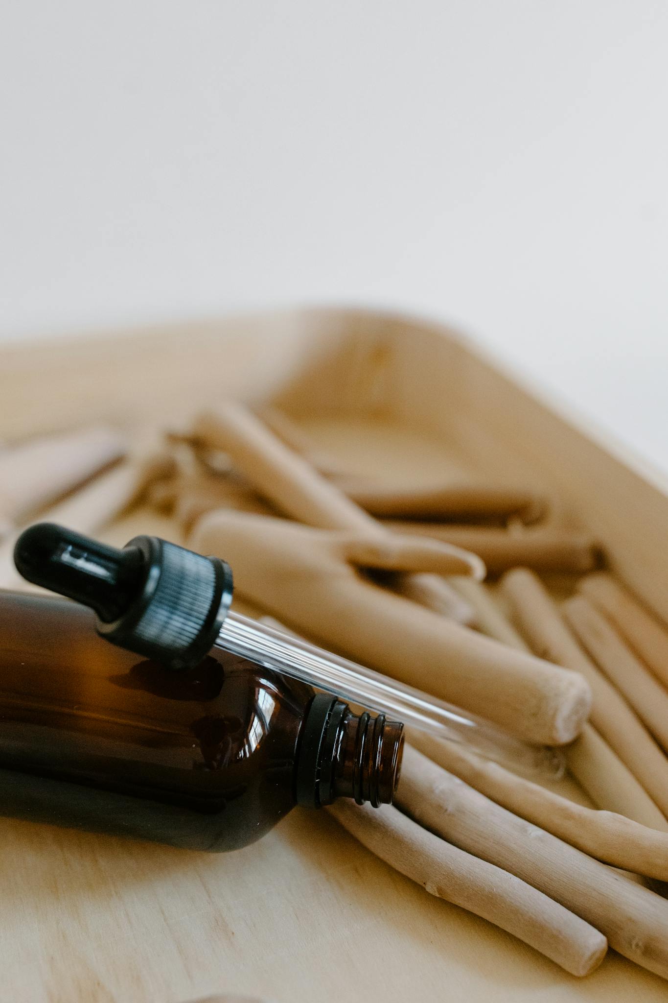 Close-up of a brown dropper bottle on wooden sticks for aromatherapy.