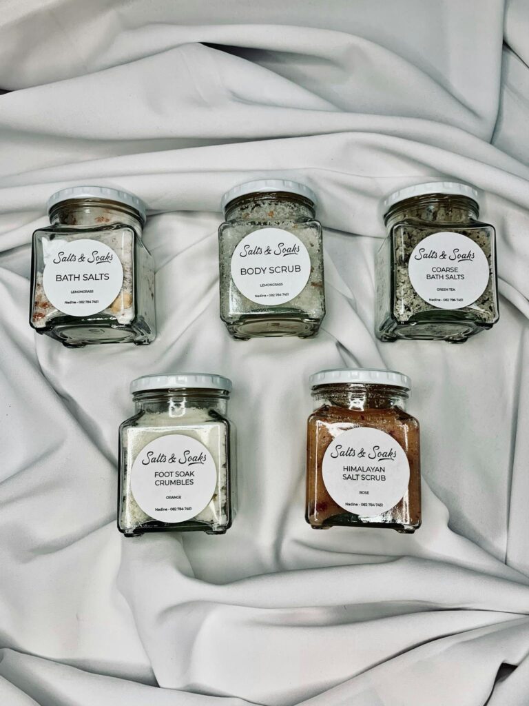 Elegant display of bath and body care products in stylish glass jars on white fabric.