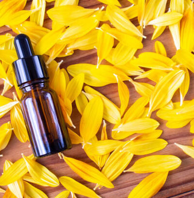 A bottle of dark glass on a background of yellow petals.