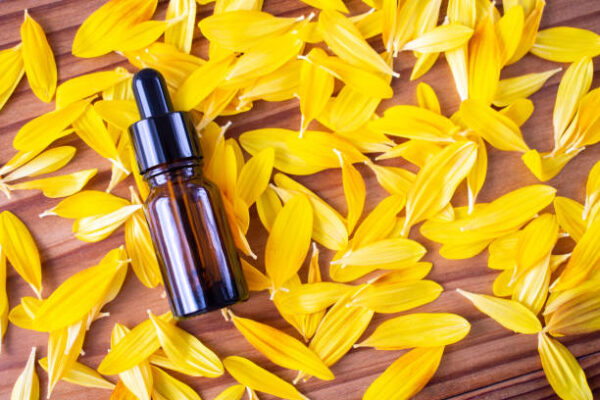 A bottle of dark glass on a background of yellow petals.