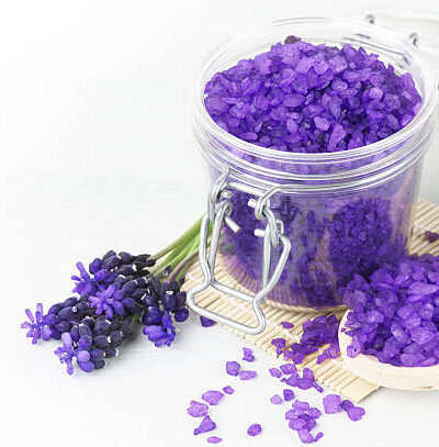 Violet bath salt in jar on white wooden background.