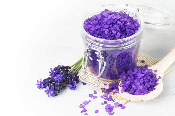 Violet bath salt in jar on white wooden background.